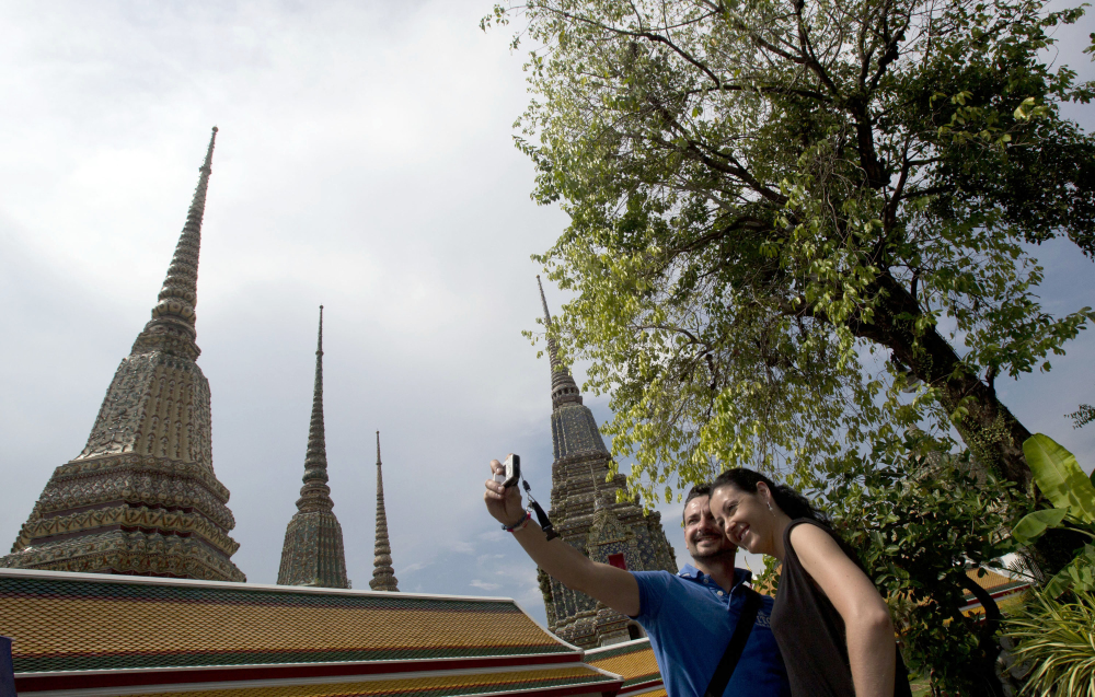 A couple of Western tourists snap a souvenir photo at a Wat Pho temple in Bangkok, Thailand Tuesday.