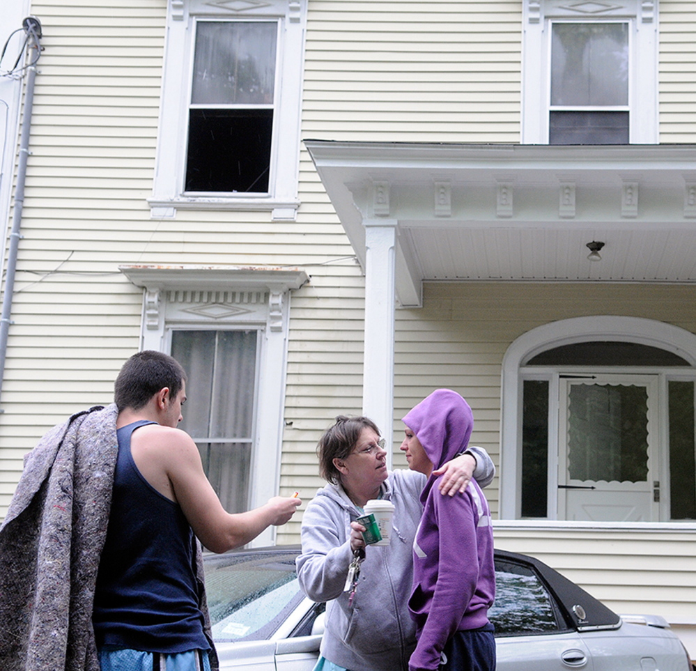 AFTERMATH: Jackie Nelson, center, hugs her granddaughter, Sabrina Moulton, the building’s owner, on Tuesday, along with tenant Anthony Luczkowski, after an early morning fire forced them to evacuate the 11 Cedar Court apartment building.
