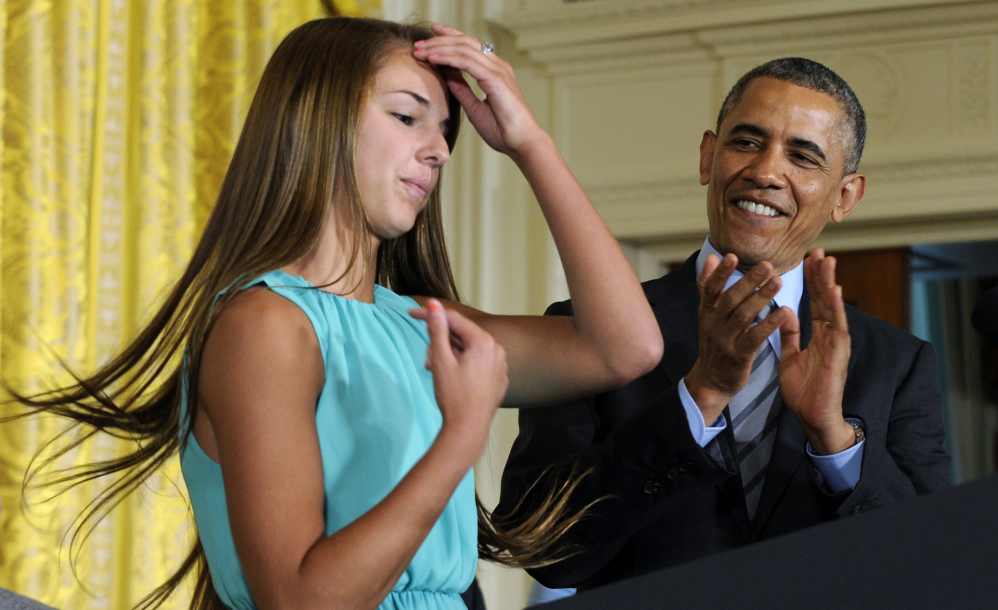 President Barack Obama applauds Victoria Bellucci, a 2014 graduate of Huntingtown High School in Huntingtown, Md., at a White House youth sports concussion summit Thursday. Bellucci suffered five concussions while playing high school and club soccer.