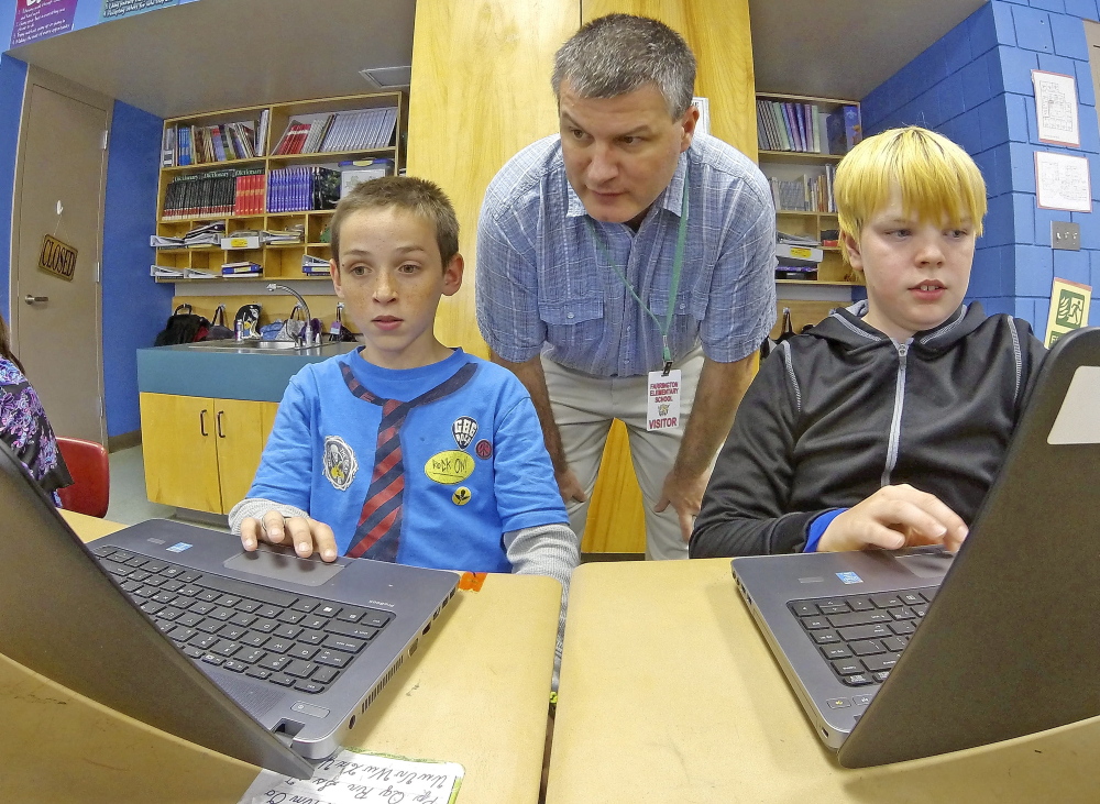 UPGRADE: Tony Paine, CEO of Kepware Technologies, center, chats with fourth-graders Gabriel Biasuz, left, and Jared Barker about how they use the laptops, that his company donated to the class earlier in the year, during a visit on Friday at Farrington School in Augusta.