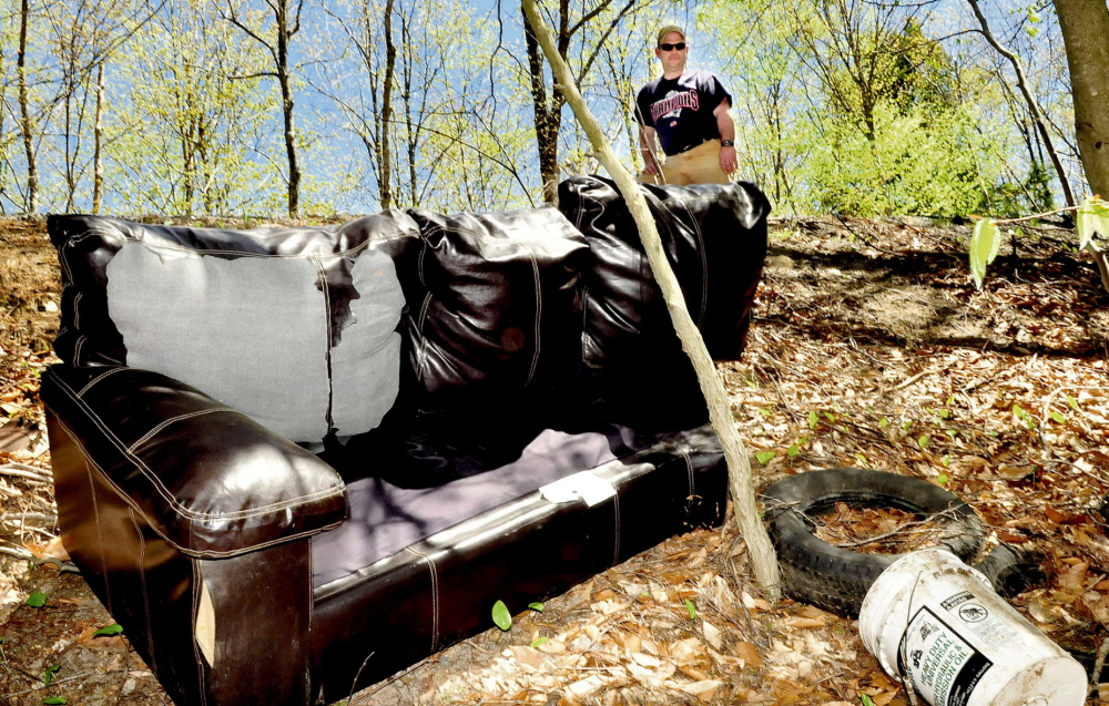 WOODLAND HEADACHE: Gary Foss, facilities manager for the town of Belgrade, looks at trash including a couch, buckets and tires that were thrown in the woods off Penney road in Belgrade. “This is unnecessary and irresponsible,” Foss said.