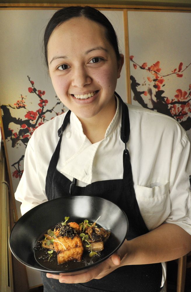 Chef Cara Stadler holds a dish of fluke with braised endive and shiitake mushrooms. For the photo, she garnished the dish with micro-greens.