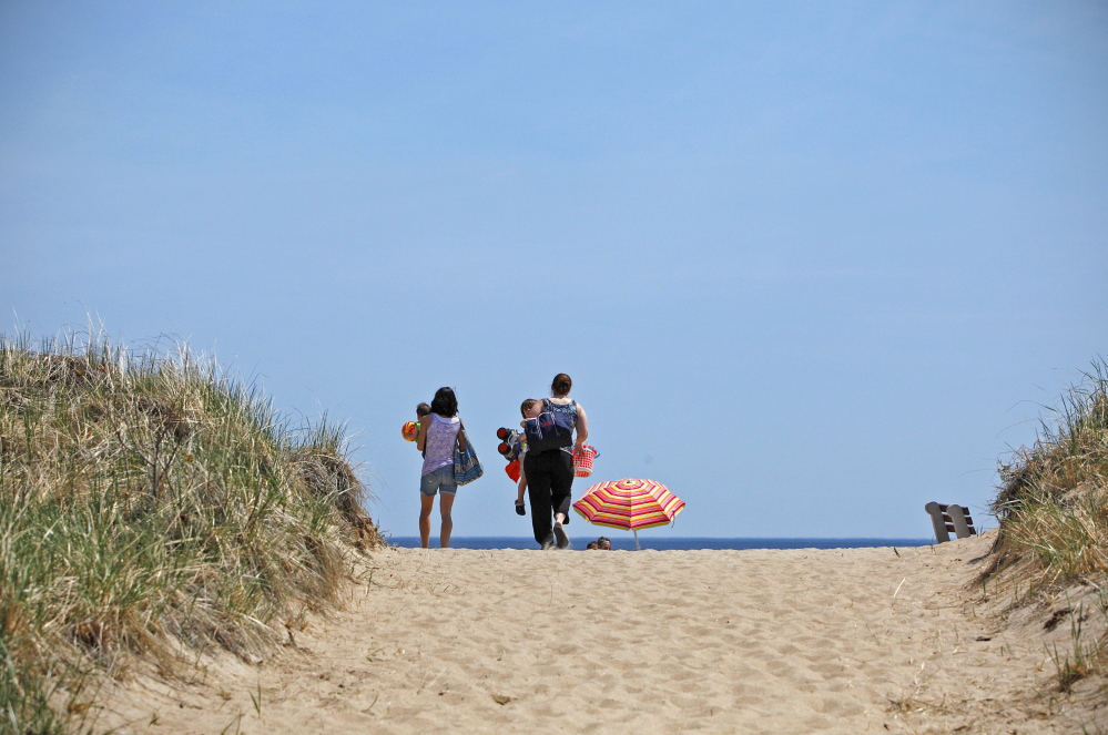 Amelia Kunhardt/Staff Photographer A family heads for the sand at Old Orchard Beach last month, on a day when temperatures climbed to near 80 degrees.