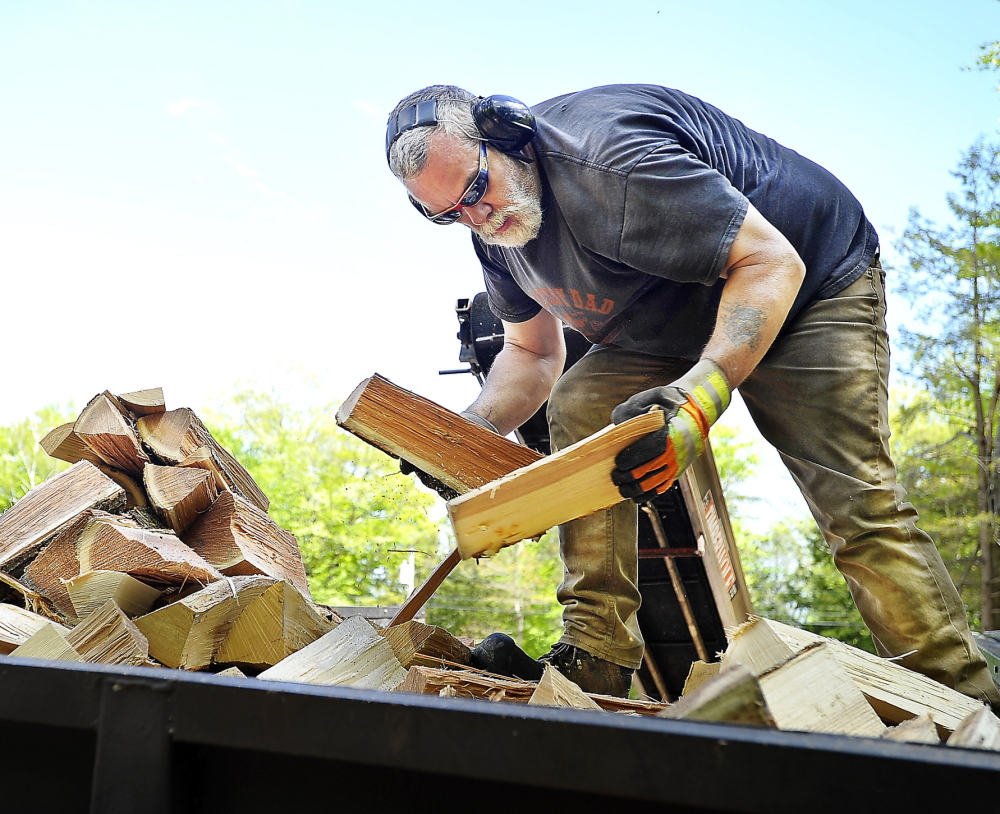 Mark Killinger, owner of Atlantic Firewood, arranges processed firewood in the bed of his truck in Windham. He and other dealers are receiving larger and earlier orders this year.