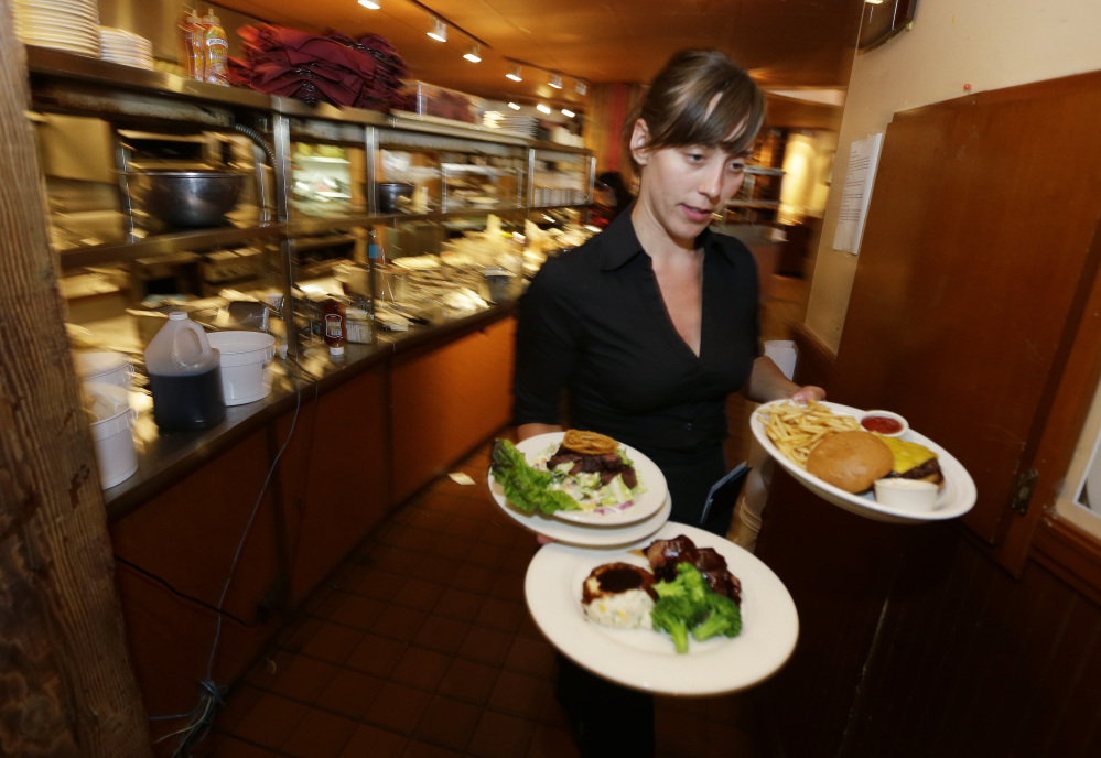 Wendy Harrison, a waitress at the icon Grill in Seattle, works during lunchtime. An Associated Press comparison of the cost of living at several other major U.S. cities found that a $15 minimum wage, like that adopted by Seattle this week, will make a difference, but won’t buy a lavish lifestyle.