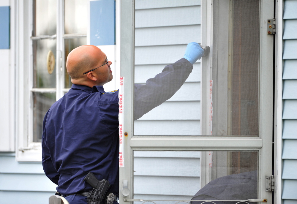 Staff photo by Michael G. Seamans Evidence: An investigator with the Maine State Police Major Crimes Unit dusts for fingerprints at the residence of Aurele Fecteau, 92, who was found dead in his home on Brooklyn Street in Waterville on Friday, May 23.