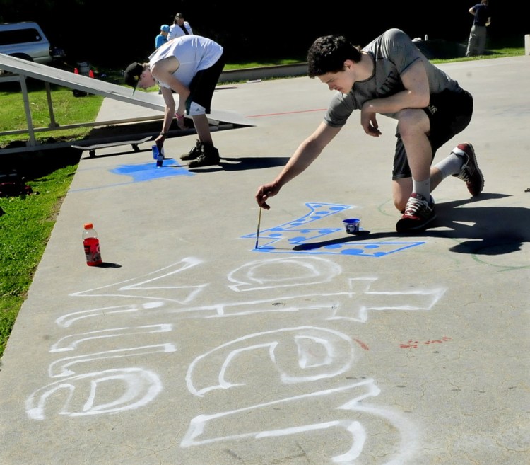 Staff photo by David Leaming BEAUTY: Waterville Senior High School student Dan Jolin, right, paints images and words at the Green Street skateboard park in Waterville as part of a beautification project Tuesday. At left Brendan Palmer works on his image.