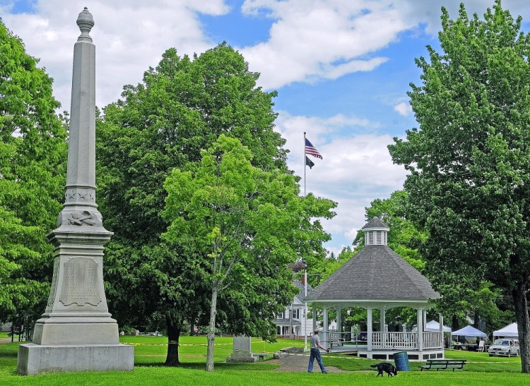 Staff photo by Joe Phelan COMMON GROUND: A man and a dog walk between a Civil War memorial and the newly built gazebo on Saturday on the Gardiner Common. The gazebo is taped off to protect the recently installed sod.