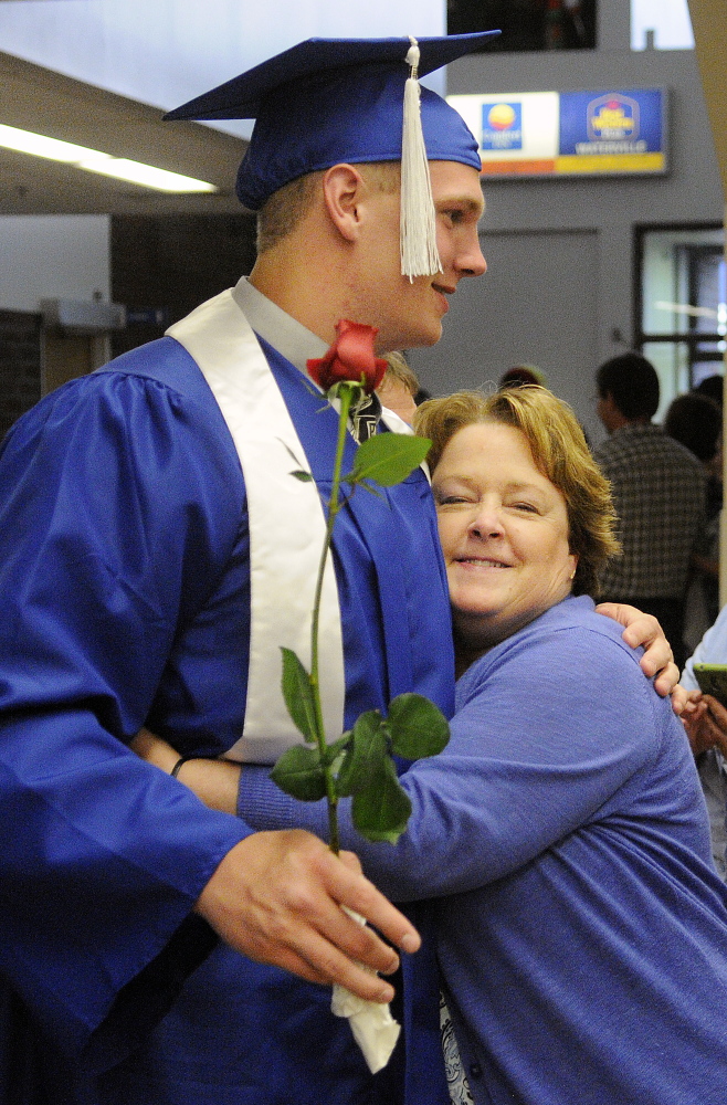 Staff photo by Andy Molloy ALL DONE: Kim Tessari hugs her nephew, Luke Washburn, Monday during graduation ceremonies in Augusta for Oak Hill High School.