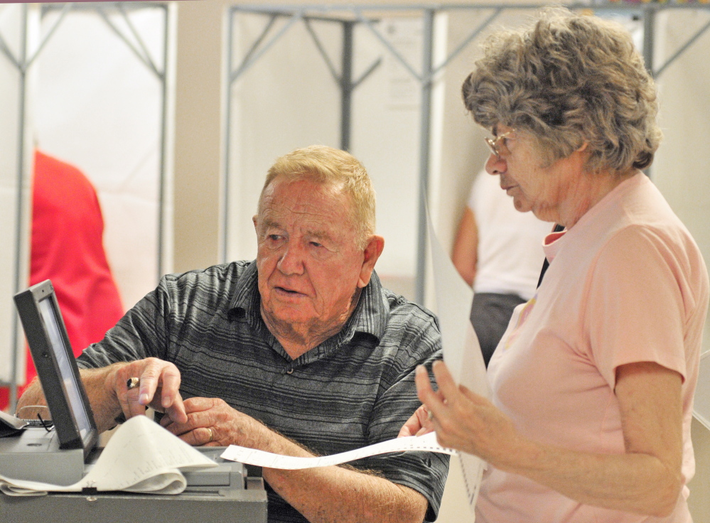 Staff Photo by Joe Phelan VOTING: Buzz Knight, left, helps resident Jackie Grenier feed her ballots into the machine Tuesday in Cumston Hall in Monmouth.