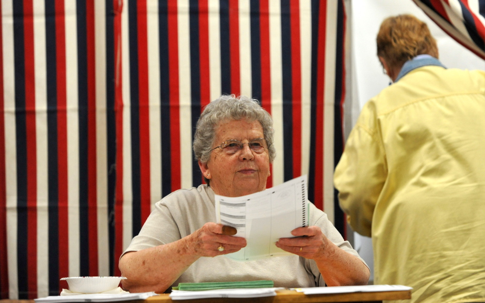 Staff photo by Michael G. Seamans 
 Loraine Arsenault, election clerk, hands out ballots at the Skowhegan Town Office during primary voting on Tuesday, June 9, 2014.