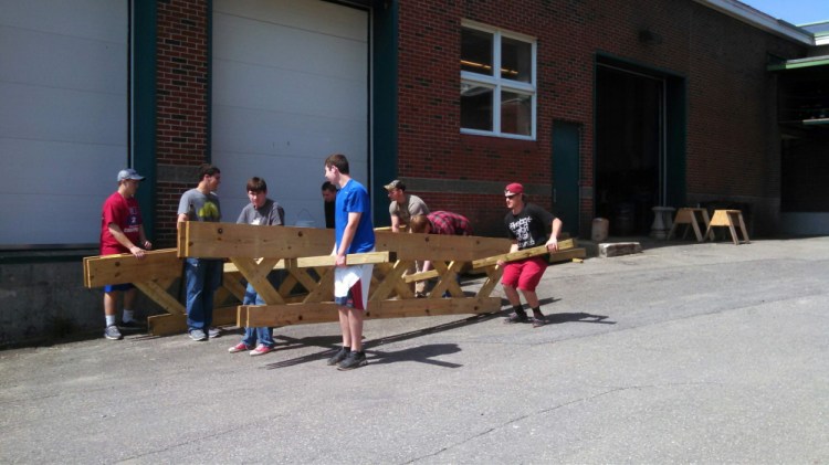 TEAM EFFORT: Students at Messalonskee High School move bridge struts that they built  as part of a walking trail system near the school. The bridge will make the walking trail easier to use.