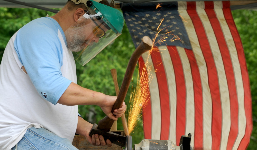 PATRIOTIC DISPLAY: Vern Burke, of Skowhegan, flies his American flag as sharpens an ax in his SwiftWater Edge Tool Works tent at his West Front Street residence on Friday. Saturday is Flag Day, commemorating the formal adoption of the stars and stripes as the official flag of the United States in 1777.