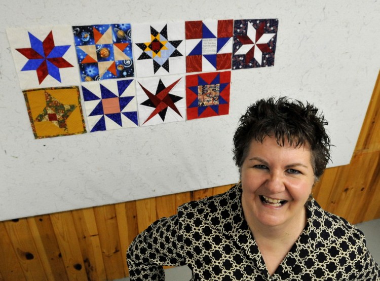 Somerset in Space: Nadine Villani, a member of the Somerset Samplers, stands next to several quilted squares with space themes at Pinwheels Quilting on West Front Street in Skowhegan on Friday. The squares will be sent to astronaut Karen Nyberg to be part of a quilt she worked on while aboard the International Space Station.