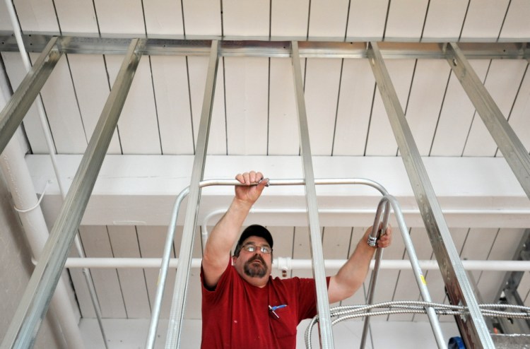 Elevated: Jon Madore, an electrical contractor with Wiswell Electric, installs conduit in a section of new MaineGeneral medical offices in the Hathaway Center on Water Street in Waterville on Thursday. Developer Paul Boghossian said retailers are interested in the space adjacent to the medical offices because of the number of people who will be working there.