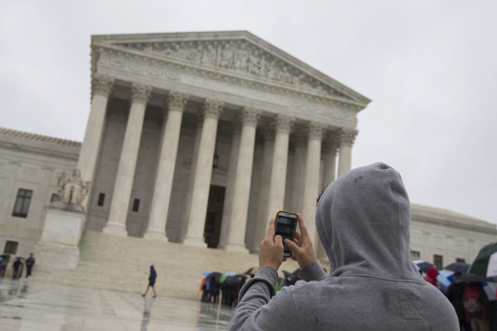 A visitor to the Supreme Court uses his cellphone to take a photo of the court in Washington. A divided Supreme Court sided with gun control groups and the Obama administration Monday, upholding a federal ban on “straw” purchases of guns.