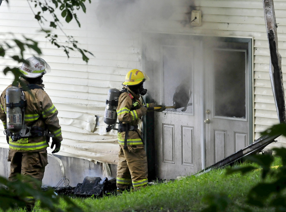 House Fire: Firefighters break glass in doors to vent fire that did extensive damage to a cottage on North Pond in Smithfield on Wednesday.