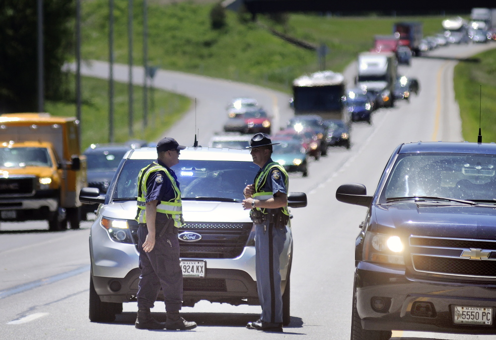 State Troopers confer Thursday June 19, 2014 on Interstate 95 in Augusta as traffic is backed up for miles due to a traffic accident that seriously injured a woman.