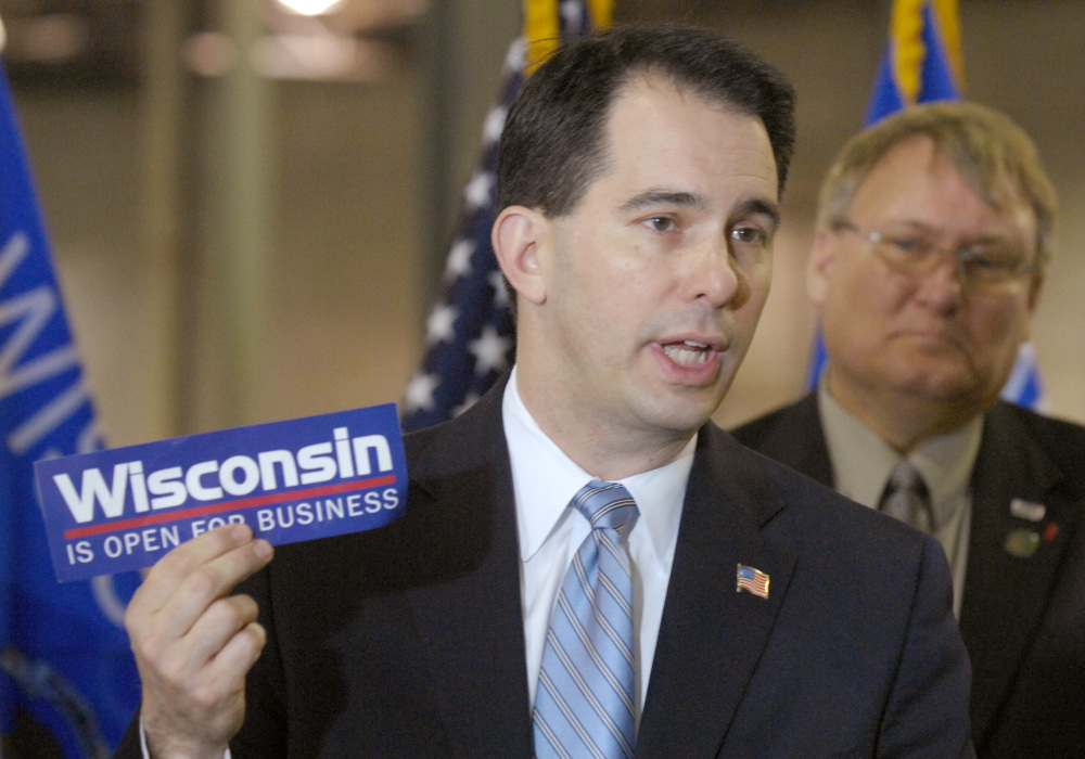 Wisconsin Gov. Scott Walker holds a bumper sticker with his signature campaign promise for the state in this 2011 photo. Walker rose to fame shortly after taking office in 2011, passing a bill that effectively ended collective bargaining for most public workers.