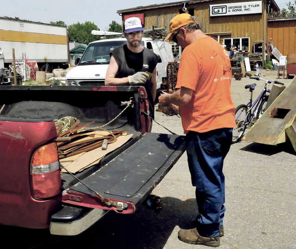 LEGAL BATTLE LOOMS: Robert Dale, left, owner of Maine 201 Antiques in Fairfield, completes a sale with customer Robert Plourde earlier this month. Dale failed to meet Sunday’s deadline for cleaning the property.