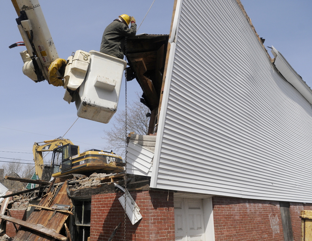 Bob Doyle hooks a rope and chain to an exterior wall of the Masonic Lodge in April during demolition of the building.