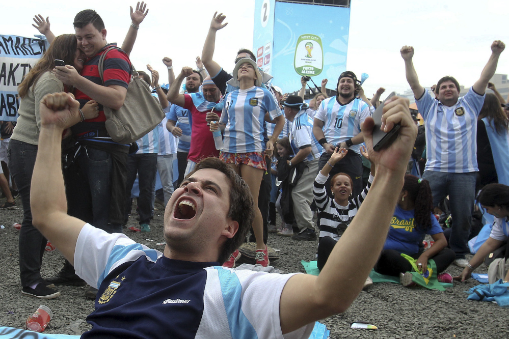 Argentina soccer fans celebrate after watching their side score a goal, via a live telecast of the World Cup group F match between Argentina and Nigeria, inside the FIFA Fan Fest area, in Porto Alegre, Brazil, Wednesday, June 25, 2014. (AP Photo/Nabor Goulart)