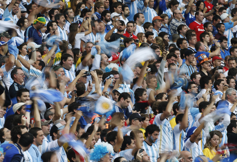 Argentine fans wave national flags Argentina's Lionel Messi is replaced after scoring two goals for his side during the group F World Cup soccer match against Nigeria at the Estadio Beira-Rio in Porto Alegre, Brazil, Wednesday, June 25, 2014. (AP Photo/Jon Super)