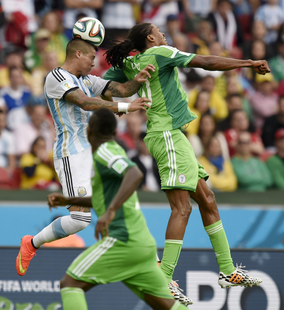Argentina’s Marcos Rojo, left, goes up to head the ball over Nigeria’s Michael Uchebo during a World Cup soccer match in Porto Alegre, Brazil, on Wednesday.