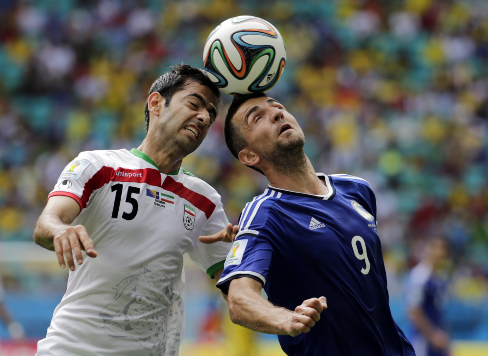 Iran’s Pejman Montazeri, left, and Bosnia’s Vedad Ibisevic battle for the ball during a group F World Cup soccer match between Bosnia and Iran at the Arena Fonte Nova in Salvador, Brazil, Wednesday, June 25, 2014.