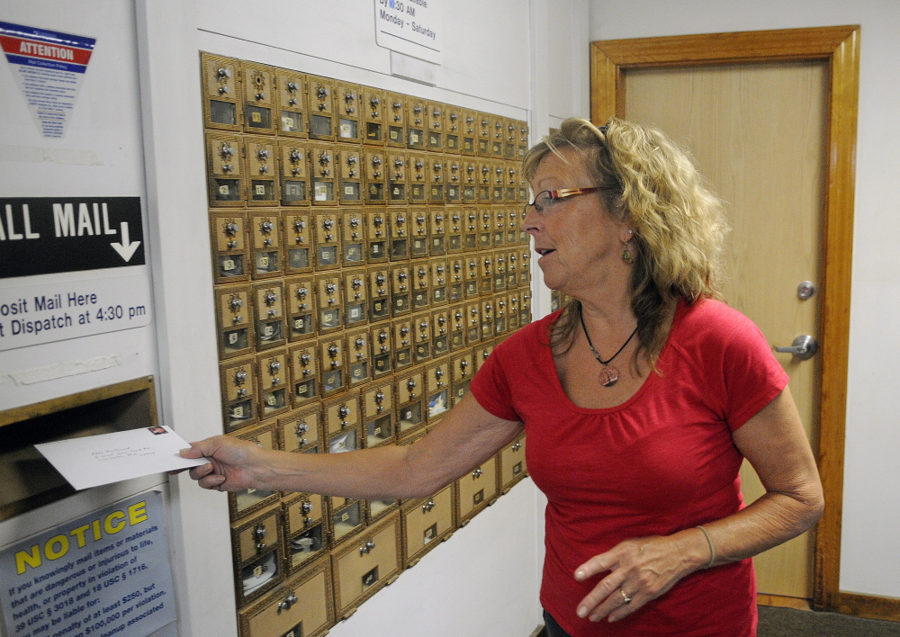 Anne Merrill mails a letter Wednesday at the post office in North Monmouth. The U.S. Postal Service plans to reduce weekday hours at the North Monmouth post office as part of a national plan to save money.