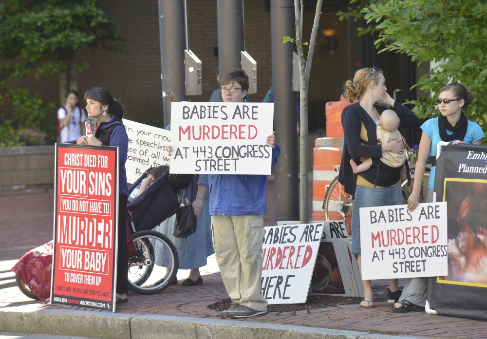 Anti-abortion activists stand across Congress Street from the Planned Parenthood of New England’s clinic in Portland on Friday.