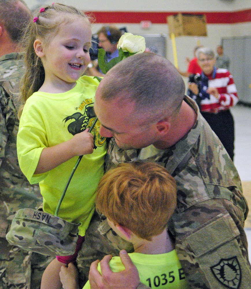 Sgt. Casy Nash, center, hugs his daughter Althea Nash, 2, top, and brother Kyle Nash, 10,  on Friday at the Augusta Armory. He had a large group of his family from Eddington there to greet him when he and the 1035th Survey and Design Team returned from Afghanistan.