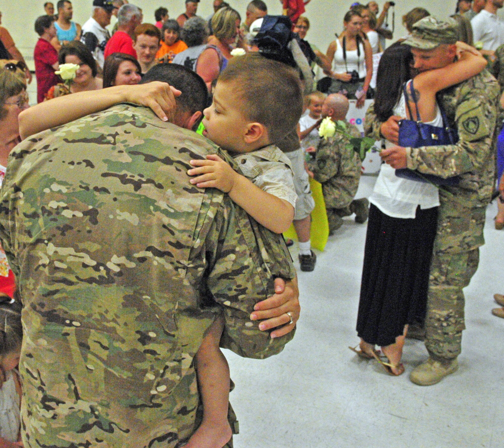 Spec. Dan Sweetser, center, is greeted by wife April Sweetser, behind him, and their son Gabriel, left, after he and the 1035th Survey and Design Team returned from a deployment in Afghanistan on Friday at the Augusta Armory.