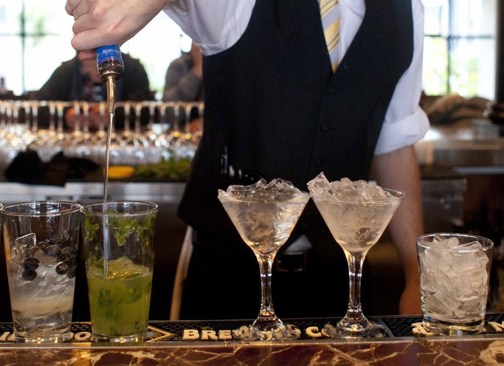 A bartender prepares alcoholic drinks at a restaurant. Researchers who prepared a recent report defined excessive drinking as five or more drinks per occasion for men and four for women.