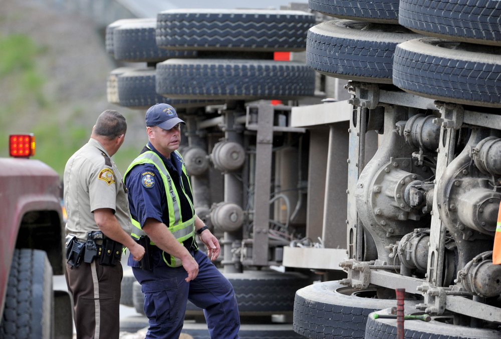 Investigators inspect a logging truck that flipped and hit an SUV on U.S. Route 201 in Moscow on Thursday. Police said Friday speed and a blown tire on the truck probably caused the crash.