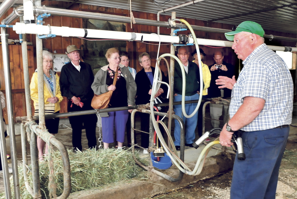 Organic dairy farmer Bussie York explains to visitors on a bus tour the process of milking cows in one of the barns at his Sandy River Farm in Farmington.