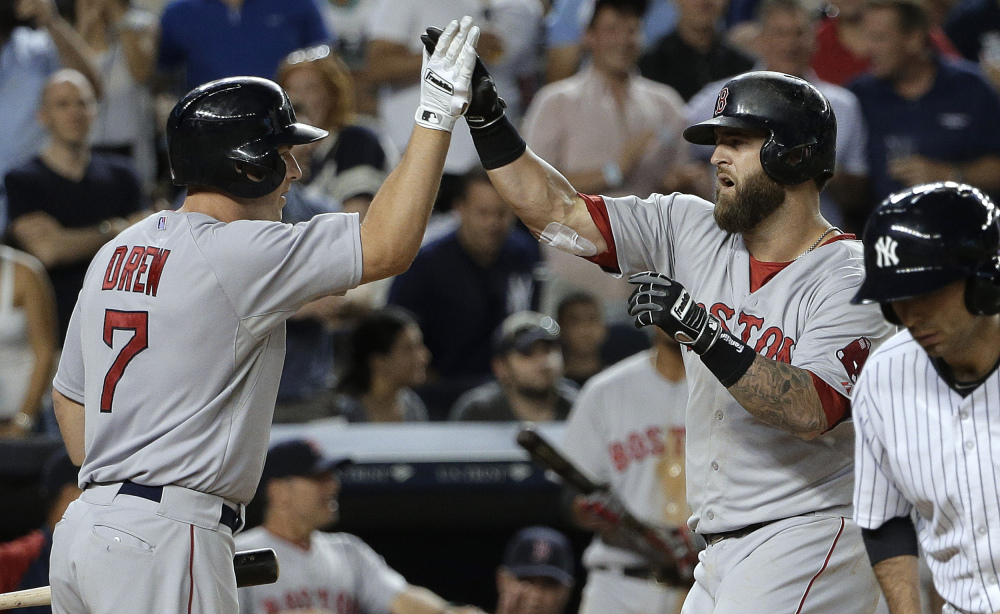 Boston Red Sox first baseman Mike Napoli, right, is greeted by Stephen Drew (7) at home plate after hitting a solo home run against the New York Yankees in the ninth inning Saturday in New York. The Red Sox won 2-1.