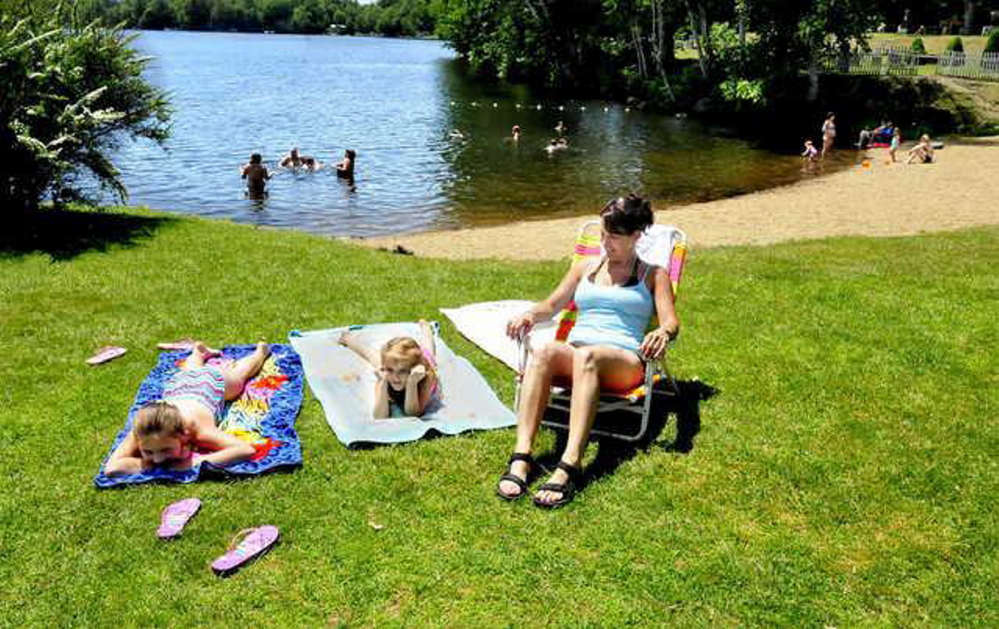 After the removal of Canada geese last week at the beach and boat launch on Messalonskee Lake in Oakland, the area should be cleaner with fewer droppings from the birds. Relaxing on a warm Monday from left are Madison and Izzy Drake and Tracy Liberty.