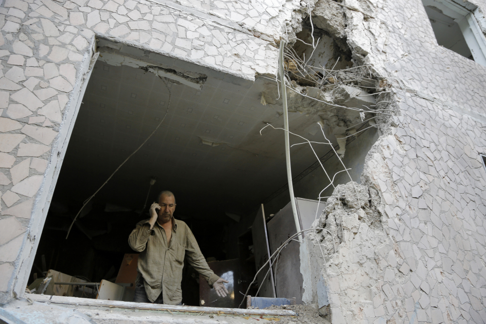 Valery, who gave only his first name, makes a phone call from a room of his damaged house after shelling in the city of Slovyansk, Donetsk Region, eastern Ukraine on Monday.