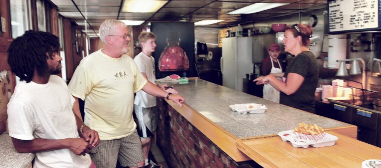 Customers including Marty Taylor, second from left, of Belgrade, wait for their food orders at Bolley’s Famous Franks restaurant in Waterville on Monda. Owner Zena McFadden, right, recently announced the business is closing this Thursday. Employee Tony Champine works at the french fry cooker.