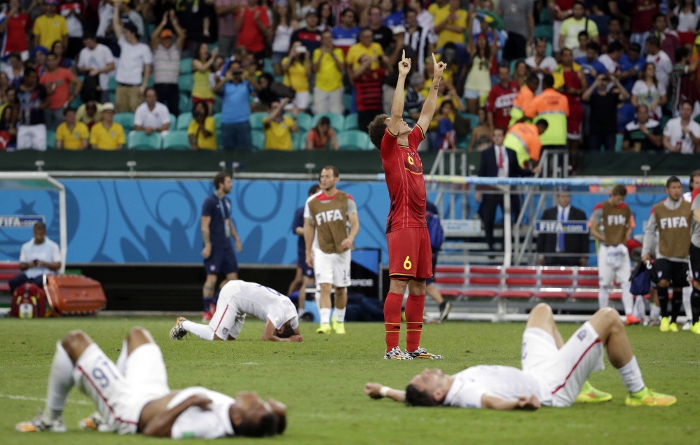 Exhausted US players lie on the ground as Belgium’s Axel Witsel celebrates at the end of the extra time after Belgium beat the US 2-1 in the knockout round of the World Cup on Tuesday in Salvador, Brazil.