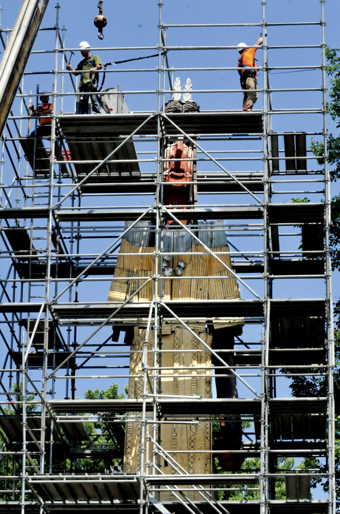 Workers from Seacoast Scaffolding erect scaffolding around the Skowhegan Indian statue for restoration of the aging piece. The arm at left is missing and there are several holes and rotted wood throughout the artwork.