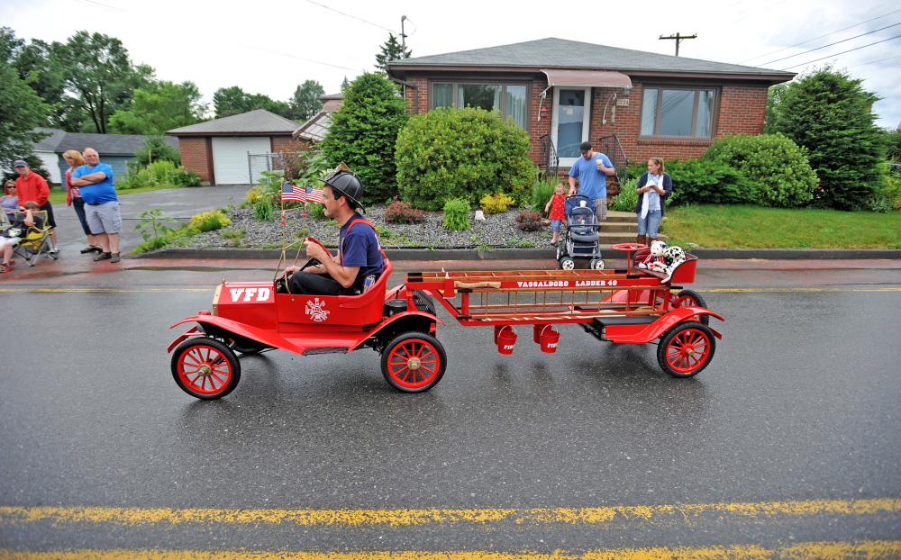A Vassalboro Fire Department firefighter drives a tiny vehicle along North Garand Street in the Wnslow Family 4th of July Celebration parade on Saturday.
