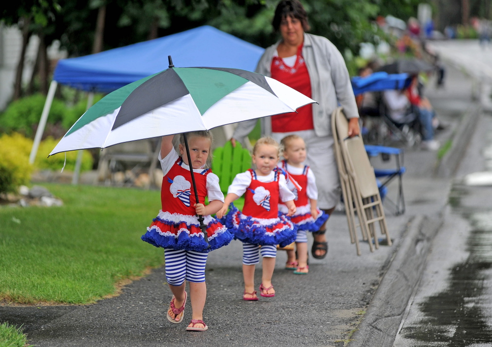 Sera Dixon, 4, leads her 2-year old twin sisters, Keira, center, and Joslin, back, with mother Shannon Dixon, far back, to a parade viewing spot on North Garand Street next to Winslow High School on Saturday. The annual Winslow Family 4th of July Celebration parade had postponed until Saturday because of rain on Friday.