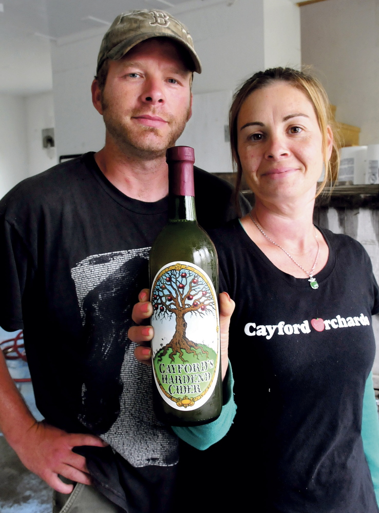 Jason and Heather Davis hold a bottle of Cayford’s Hardened Cider, which they make at their business, Cayford’s Orchards.