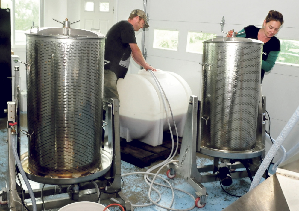 Jason and Heather Davis work around equipment as apple syrup processes in tanks Thursday at Cayford’s Orchards in Skowhegan. The Davises have diversified. In addition to making cider, they now make hard cider and apple syrup and soon will make apple vinegar.