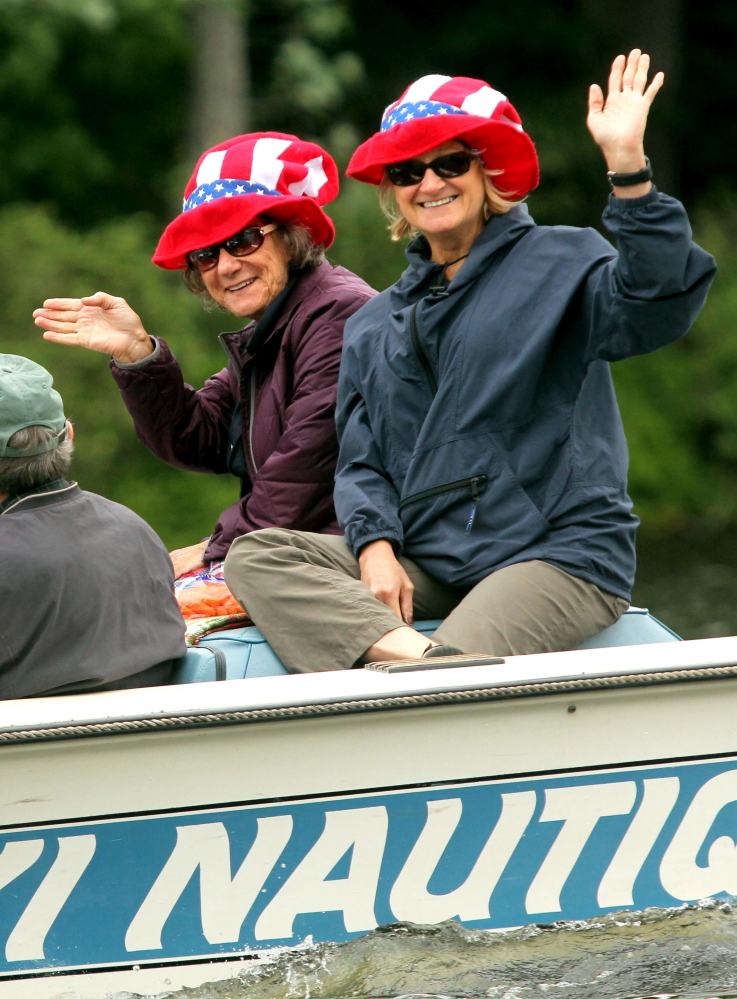 Boaters wave to a crowd lined up along Mill Stream on Saturday to watch the annual boat parade to celebrate Independence Day in Belgrade Lakes village.
