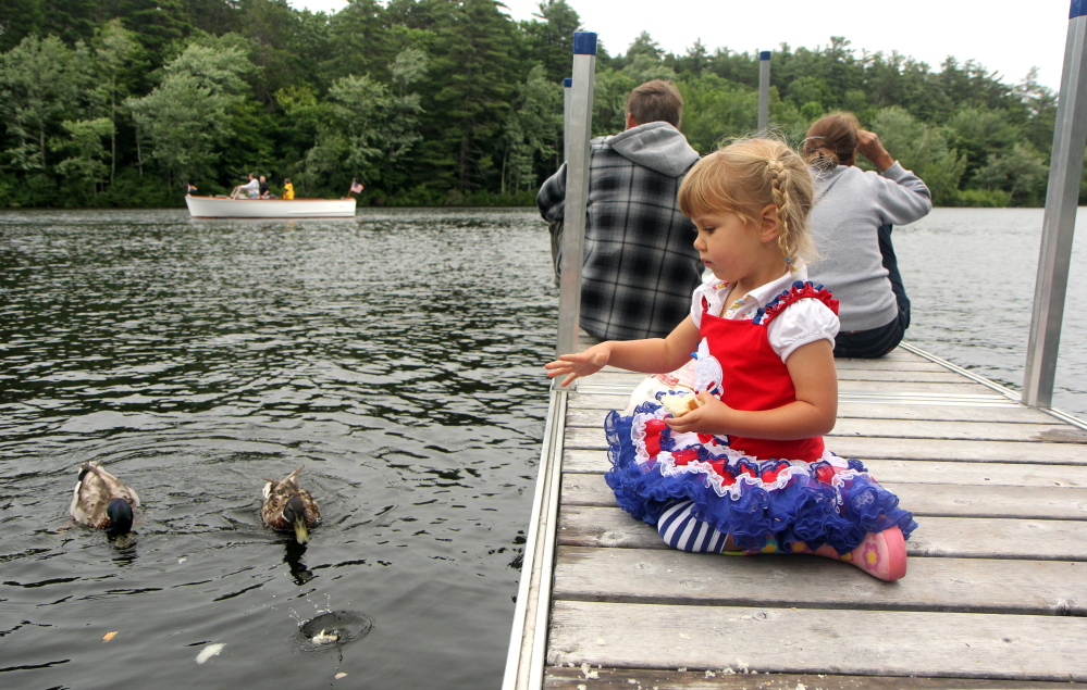 Sunniva Saal, 2, of Rome feeds some ducks Saturday as pectators take in the annual boat parade to celebrate Independence Day in Belgrade Lakes village.
