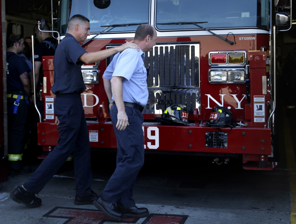 Firefighters comfort one another after bunting was hung in honor of Lt. Gordon Ambelas in New York on Sunday.