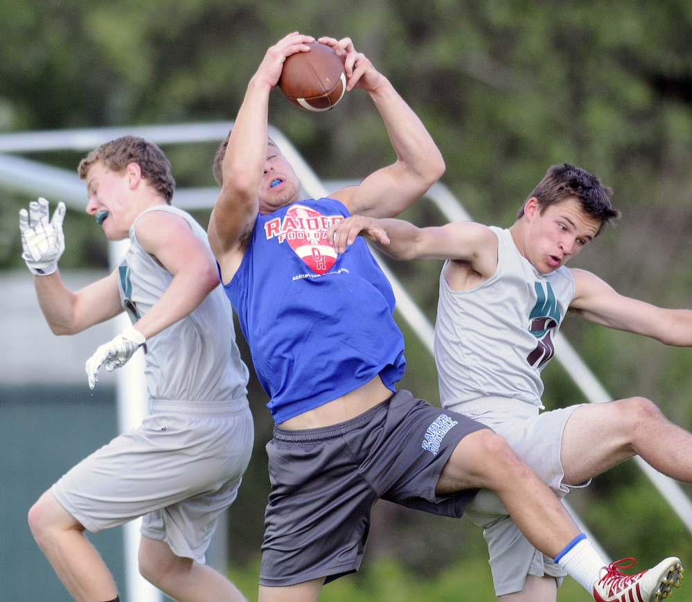 An Oak Hill High School player receives a pass between Winthrop-Monmouth players on Sunday, July 6, 2014 during the annual 7x7 football tournament in Turner.
